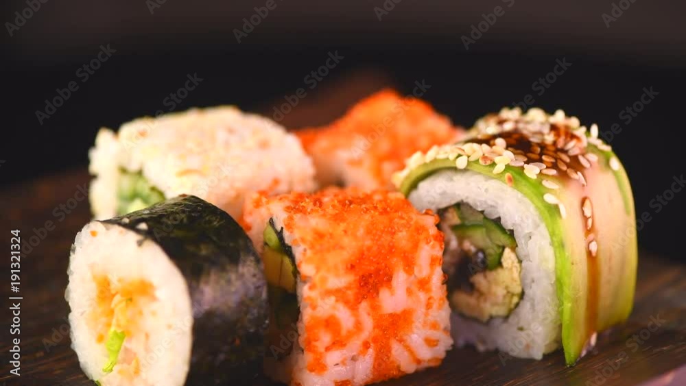 Sushi rolls set rotated over black background. Japanese restaurant sea food menu. 4K UHD video footage. 3840X2160