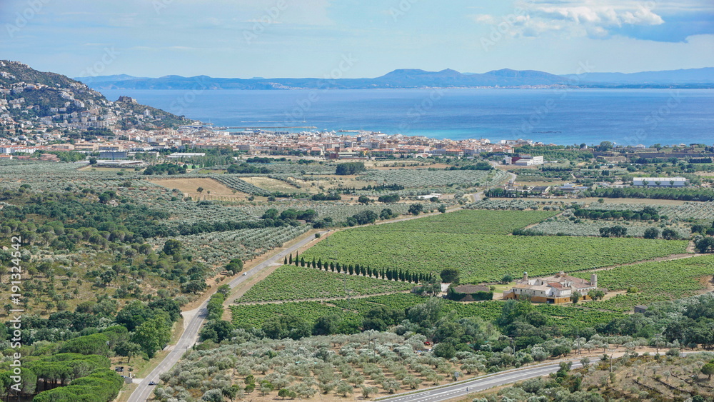 Spain Costa Brava view over vineyards fields and olive groves with the Mediterranean sea and the city of Roses, Girona, Catalonia, Alt Emporda
