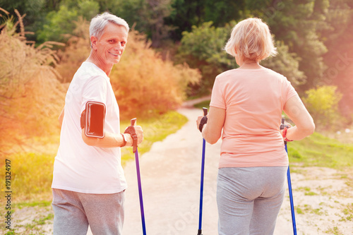 Expressing happiness. Elderly man looking at you with a smile while having pleasant walk with his wife