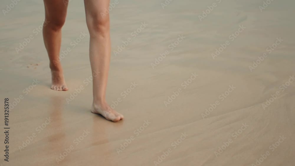 Woman legs walking on the beach sand waves sea Woman legs walking on the beach sand waves sea