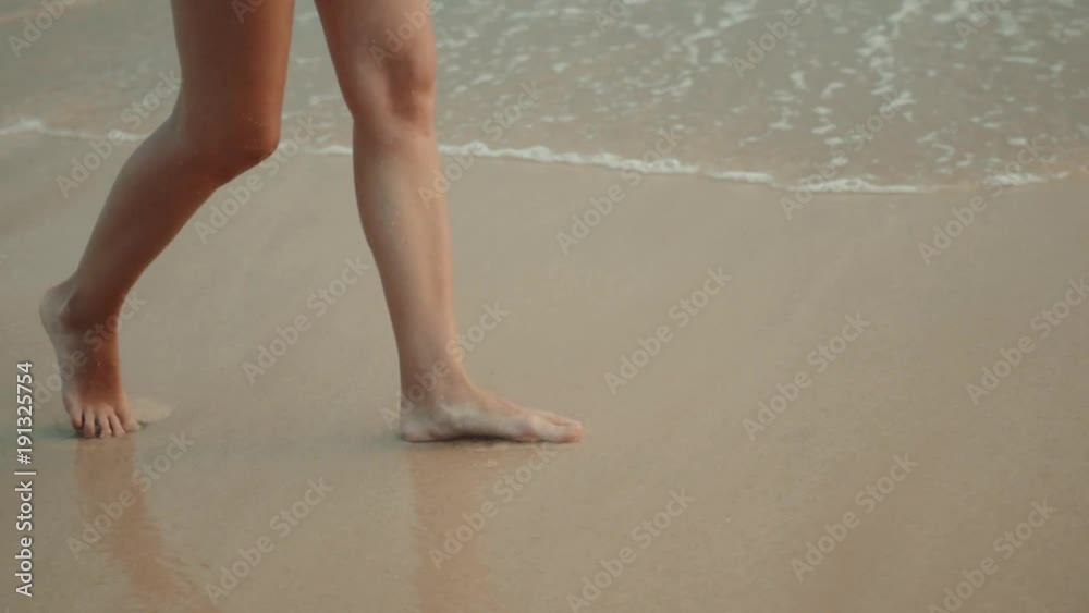 Woman legs walking on the beach sand waves sea Woman legs walking on the beach sand waves sea