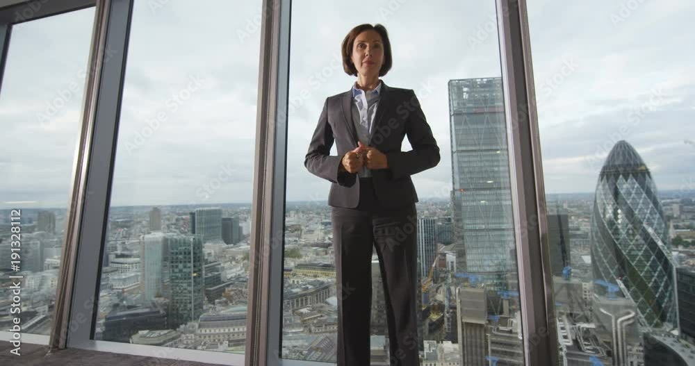 4K Portrait serious mature businesswoman in London city office. View from the window shows famous skyline with iconic buildings. Slow motion. 4K Portrait serious mature businesswoman in London city office. View from the window shows famous skyline with iconic buildings. Slow motion.