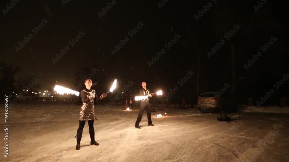 Amazing tribal fire show dance at night on winter under falling snow. Dance group performs with torch lights and pyrotechnics on snowy weather. Amazing tribal fire show dance at night on winter under falling snow. Dance group performs with torch lights and pyrotechnics on snowy weather.