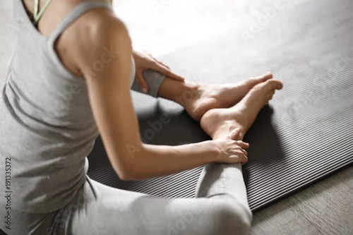 Fototapeta samoprzylepna Zrelaksowana młoda sportsmenka robi joga i medytuje w studiu