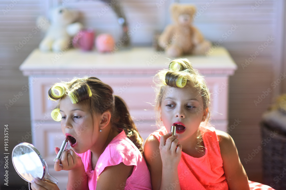 Little girls do makeup sitting in room with toys