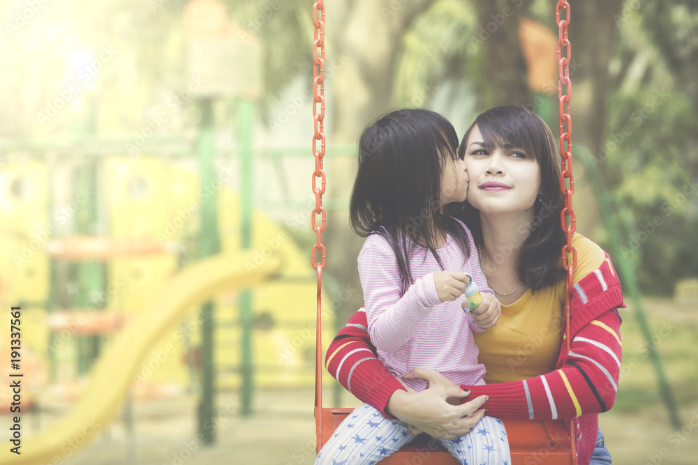 Daughter kisses mother at playground Daughter kisses mother at playground