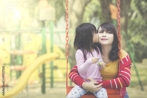 Daughter kisses mother at playground © Creativa Images