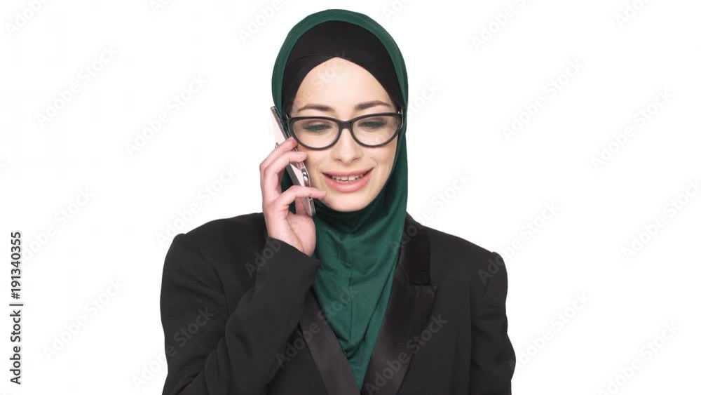 Portrait of happy arabian female employee in headscarf having successful job negotiations on cell phone, over white background. Communication and technology concept Portrait of happy arabian female employee in headscarf having successful job negotiations on cell phone, over white background. Communication and technology concept