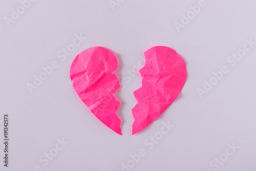 Broken heart made of pink crumpled paper on a bright background. Card with space for text. photo