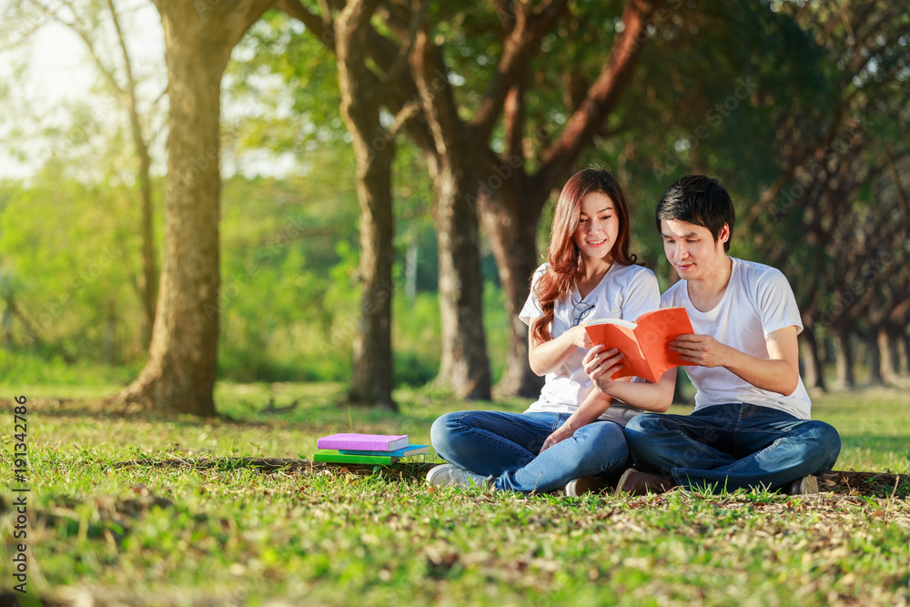 man and woman sitting and reading a book in park man and woman sitting and reading a book in park
