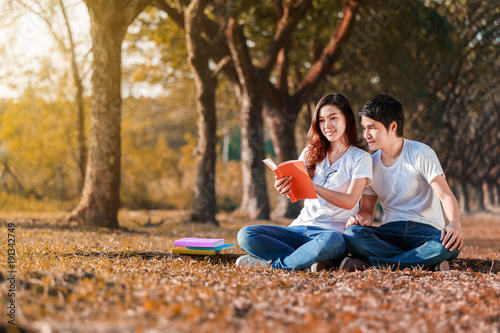 man and woman sitting and reading a book in park