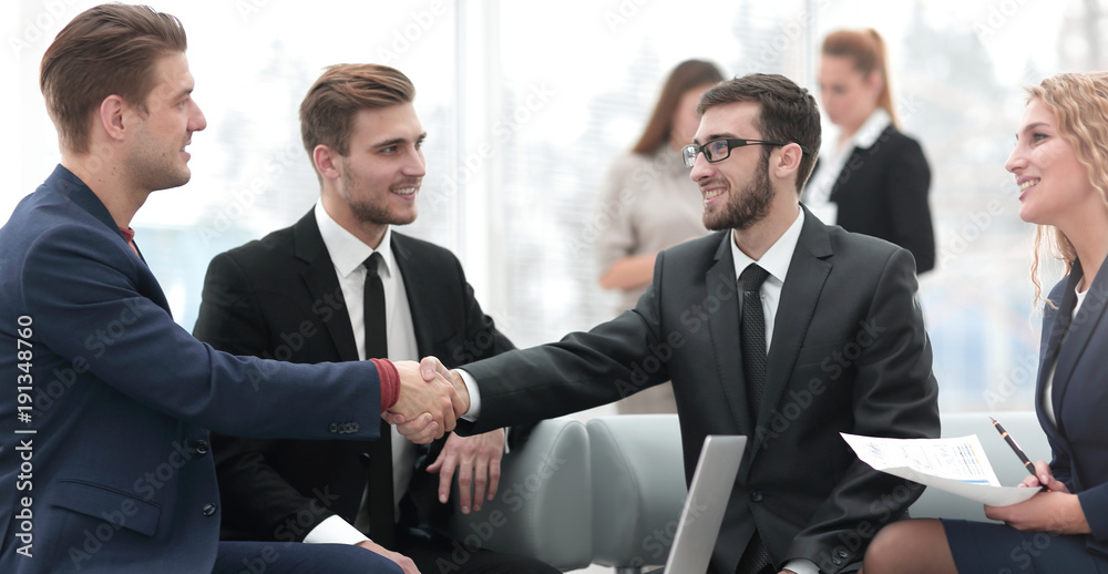 Partners concluding deal and shaking hands in the presence of team members