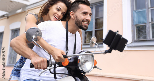 Happy couple on scooter making selfie on smartphone outdoor © ASDF