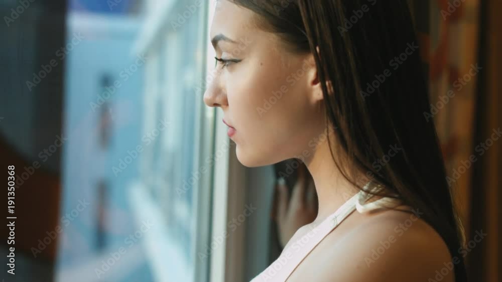 Portrait of brunette standing by the window and admiring the view Portrait of brunette standing by the window and admiring the view