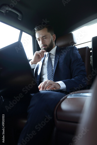 businessman working with laptop and looking out the window of a car © ASDF