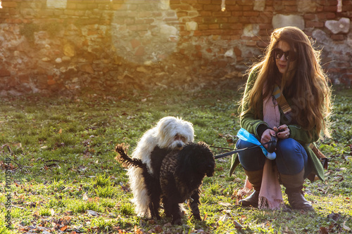 Young woman watching and smirking at two puppies humping each other in the park on a sunny day