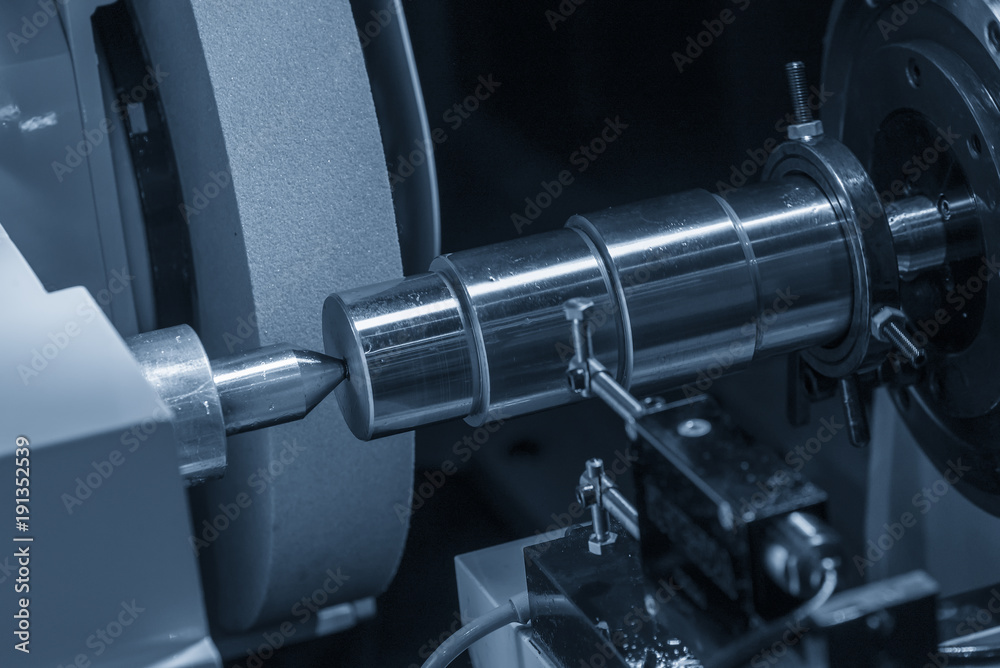 The cylindrical grinding machine with the steel shaft.Hi precision manufacturing concept. The cylindrical grinding machine with the steel shaft.Hi precision manufacturing concept.