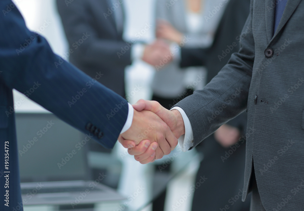 Business partners handshaking over business objects on workplace Business partners handshaking over business objects on workplace