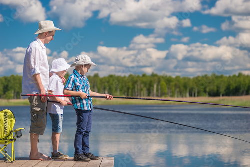 on a wooden pier the father teaches his sons to fish properly