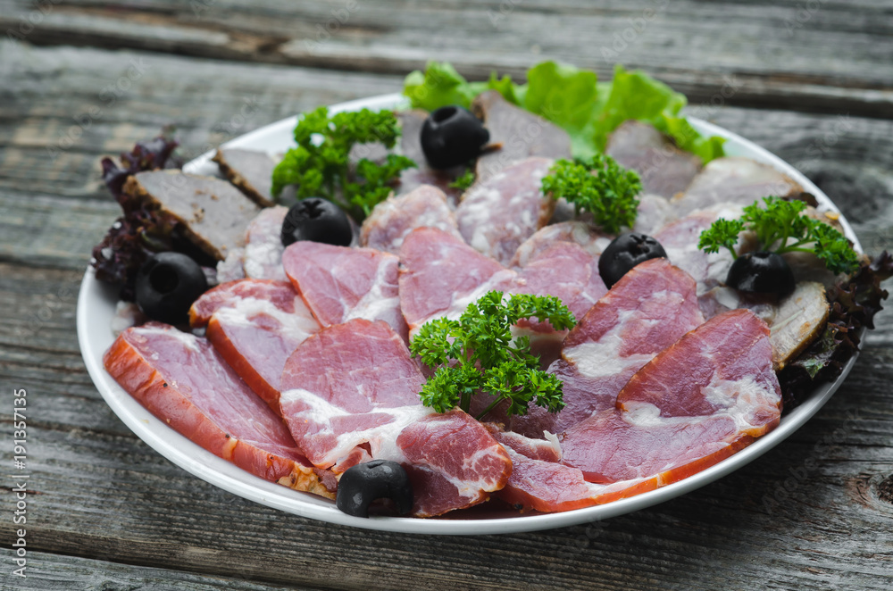 nicely sliced meat on plate, on wooden background in rustic style