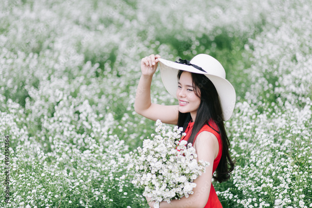 Portrait young woman in red dress smelling white cutter flower in garden.