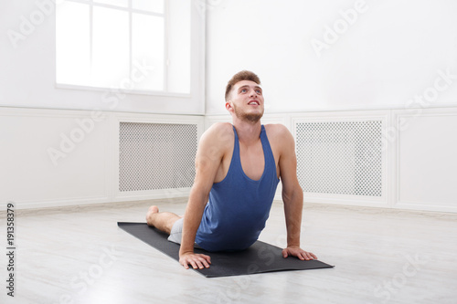 Man training yoga in cobra pose, copy space