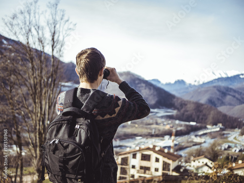 Tourist backpacking watches through binocular in the mountain village