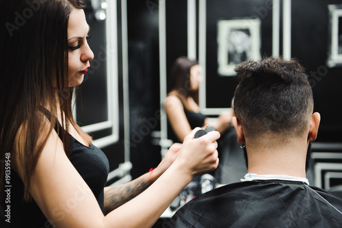 Master cuts hair and beard of men in the barbershop, hairdresser makes hairstyle for a young man