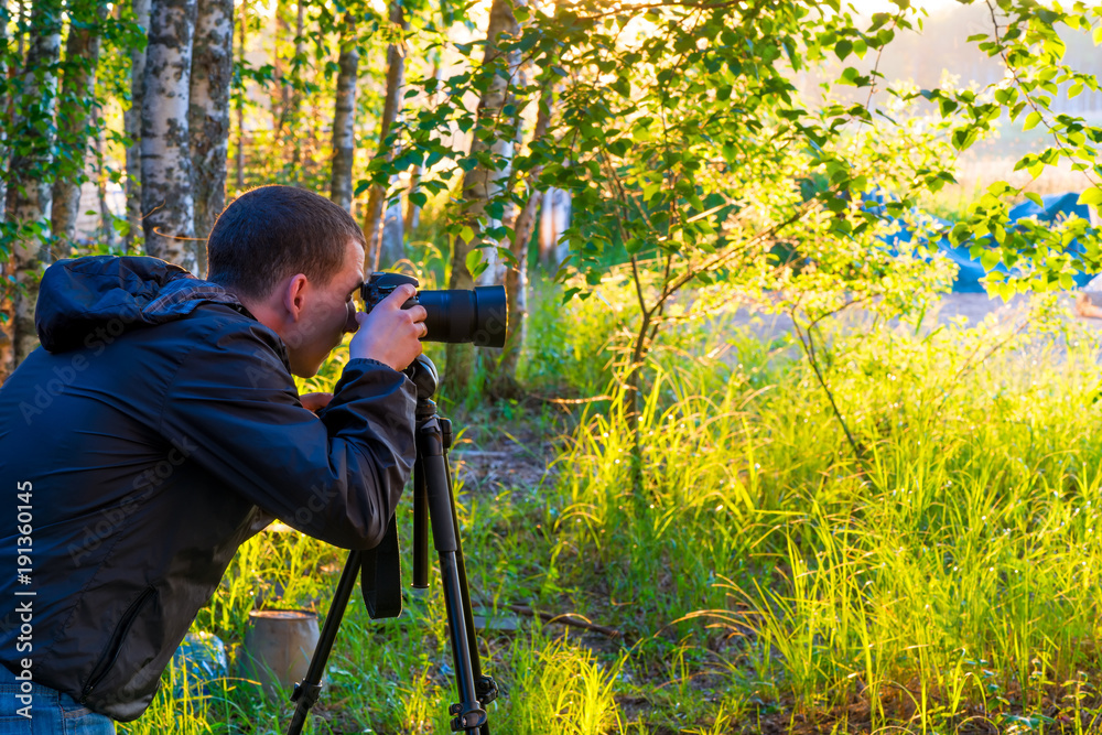 A man with a camera on a tripod takes pictures of nature