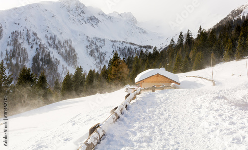 Panoramic view of idyllic winter wonderland with mountain tops and traditional mountain chalet in the Dolomites