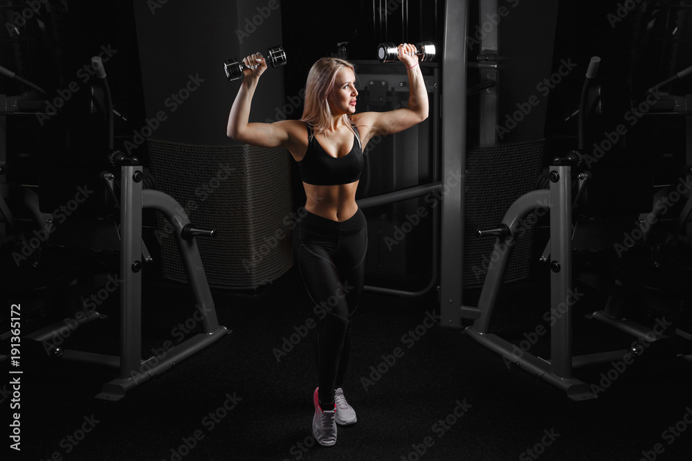 athletic young woman doing a fitness workout with dumbbells