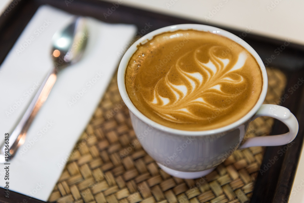 Hot cappuccino art with spoon and tissue paper on wooden plate, Top view Hot cappuccino art with spoon and tissue paper on wooden plate, Top view