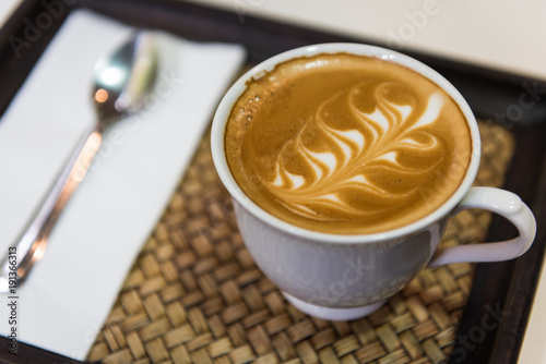 Hot cappuccino art with spoon and tissue paper on wooden plate, Top view