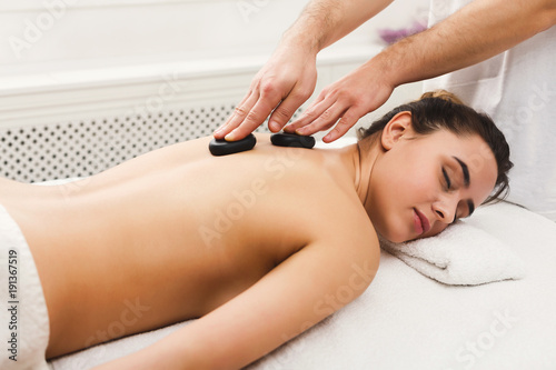 Woman getting hot stones massage at spa salon
