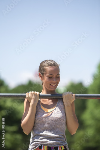Woman doing lifting up on the gym bar at summer