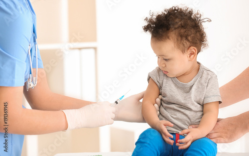 Doctor vaccinating little b...
