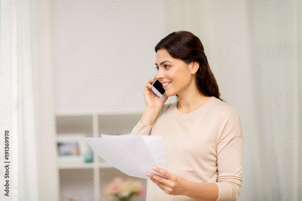 woman with papers calling on smartphone at home woman with papers calling on smartphone at home