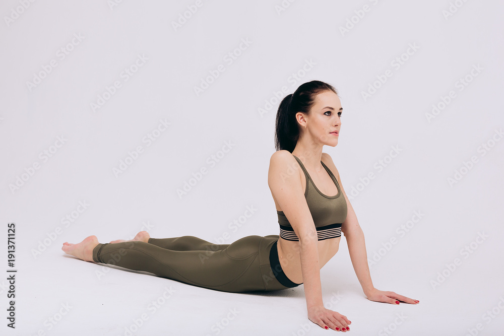 Gymnast girl performs stretching exercises on the white background 