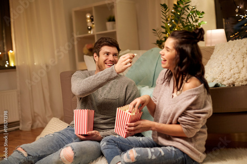 happy couple eating popcorn at home