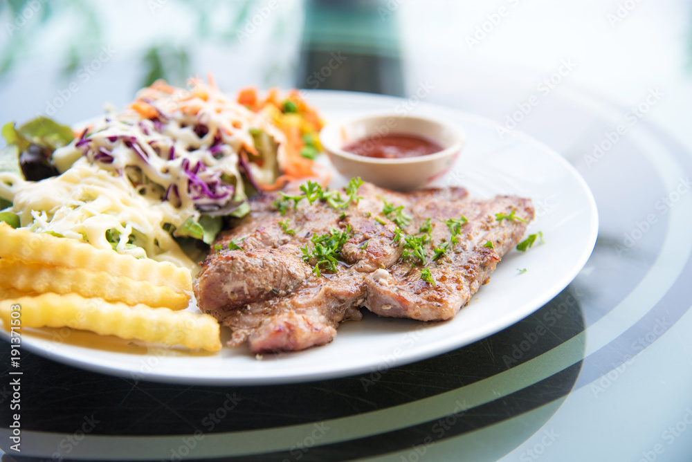 Pork chop steak with salad and gravy sauce in dish. Food and Vegetable concept. Restaurant and menu theme. Pork chop steak with salad and gravy sauce in dish. Food and Vegetable concept. Restaurant and menu theme.