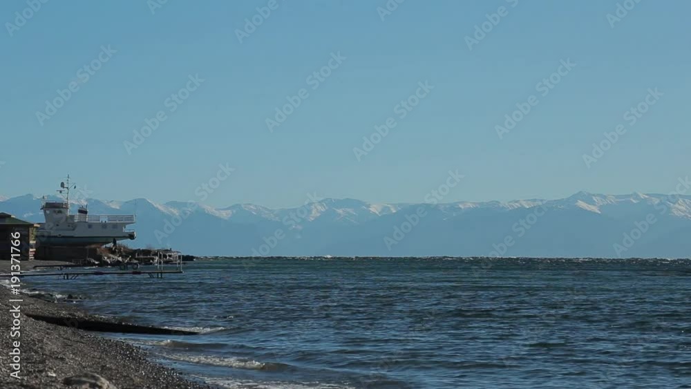 View of the Baikal lake coast. Pure water, waves. Clear day. There are mountains on the other side of the lake. View of the Baikal lake coast. Pure water, waves. Clear day. There are mountains on the other side of the lake.