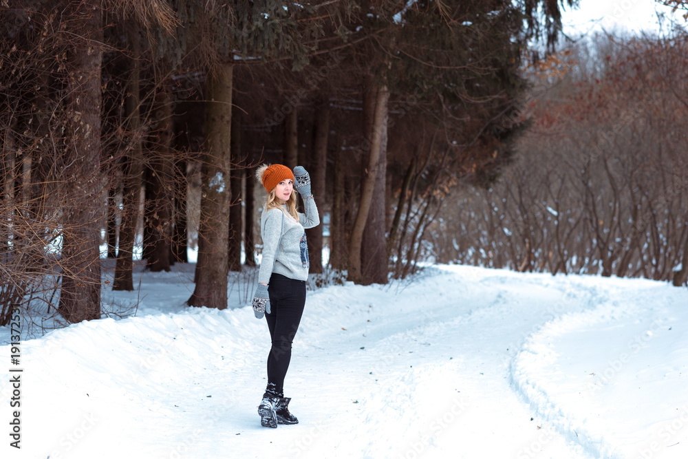 beautiful girl in a fur vest walks in a field in the snow