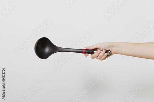 Close up of female hand horizontal holding black ladle dipper isolated on white background. Kitchen utensils concept. Copy space for advertisement.