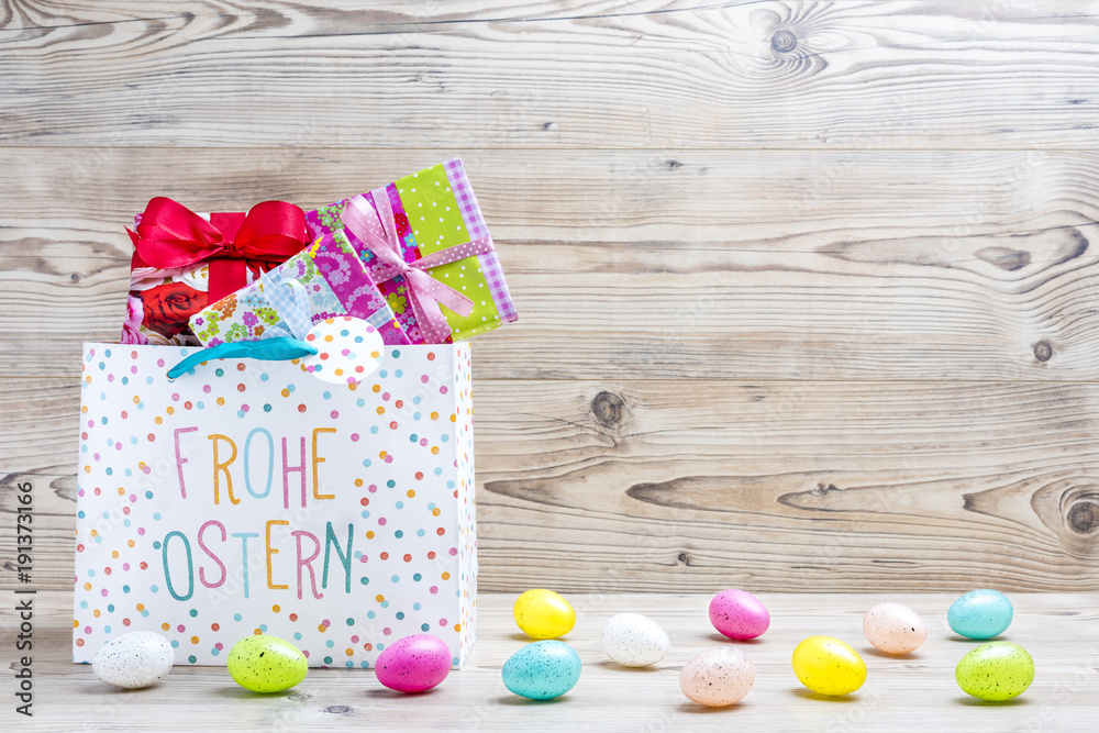 Obraz premium Ostergeschenke und Ostereier vor einem Holz Hintergrund