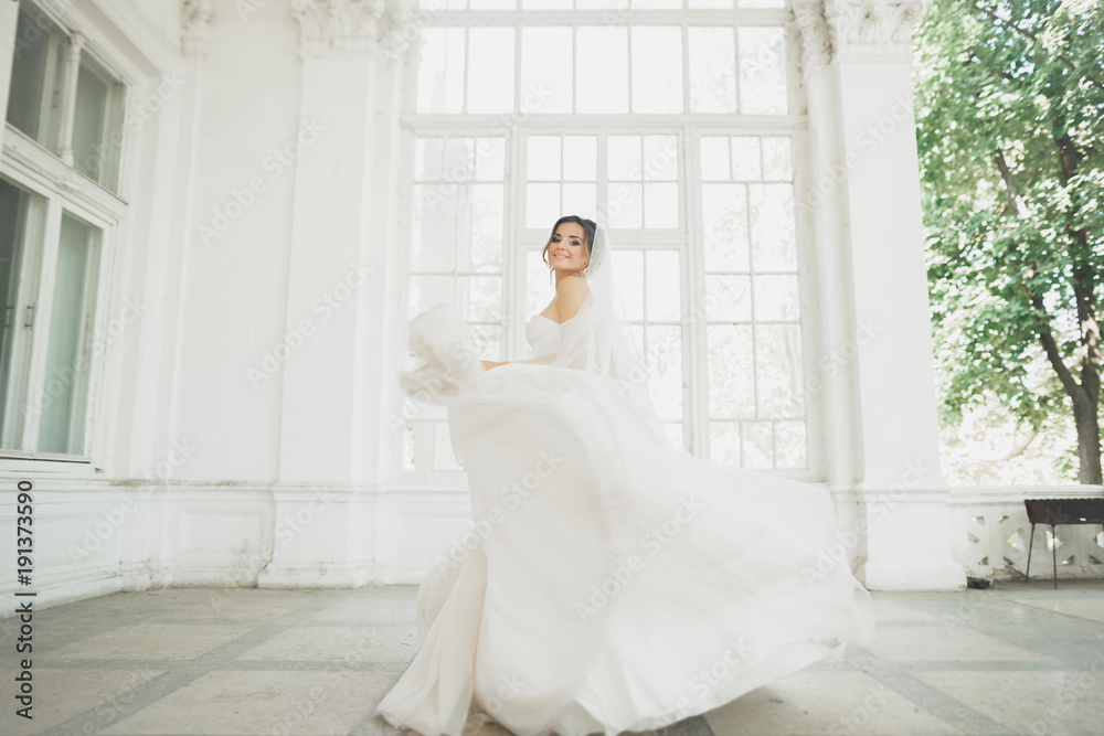 Beautiful bride in wedding dress with long full skirt, white background, dance and smile Beautiful bride in wedding dress with long full skirt, white background, dance and smile