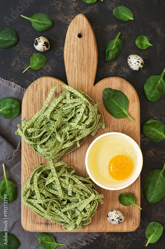 Dry macaroni nests with spinach. Pasta green on a dark background with spinach leaves. photo