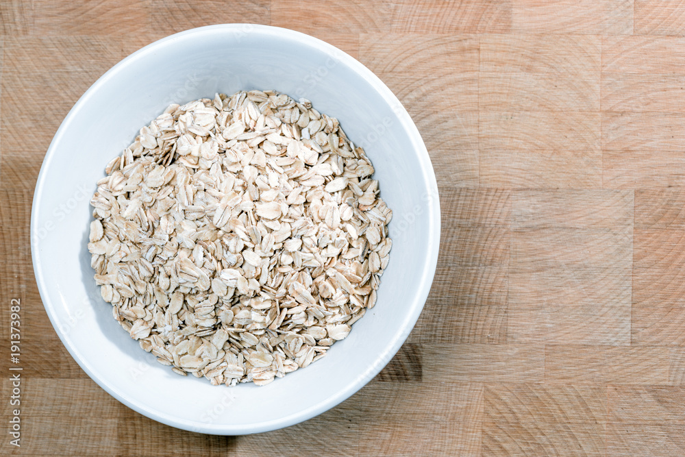 white bowl of oat flakes on wooden table white bowl of oat flakes on wooden table