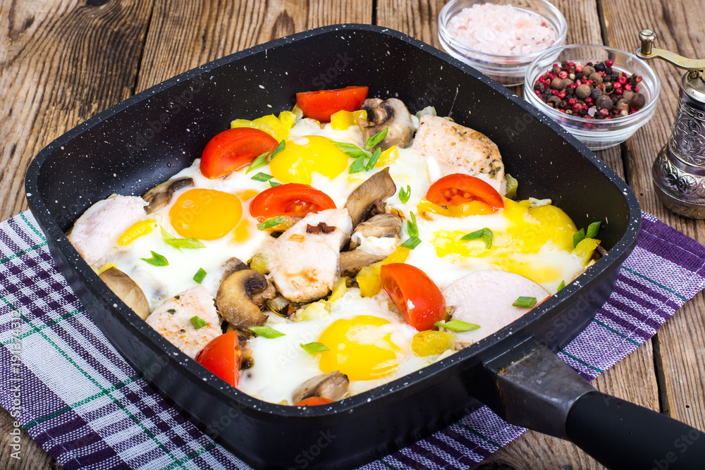 Fried eggs, tomatoes, ham, mushrooms in frying pan Fried eggs, tomatoes, ham, mushrooms in frying pan