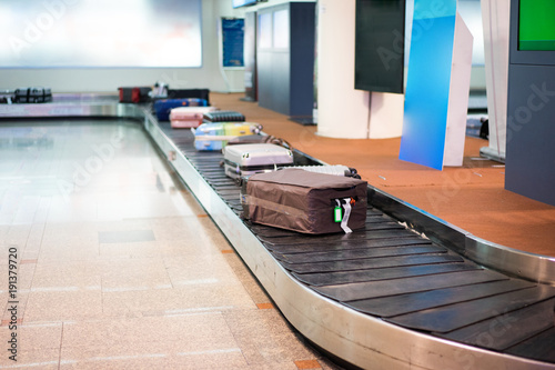 Many luggages are laying down on the conveyor belt at the airport.