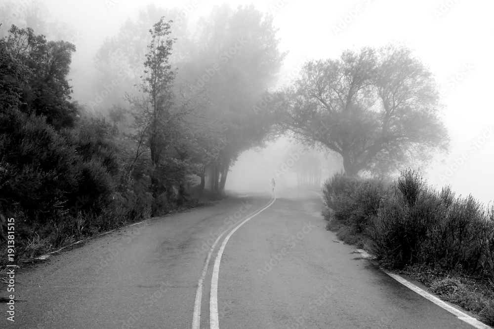 Road to nowhere. Woman walking in fog nature, on the middle a mountain road